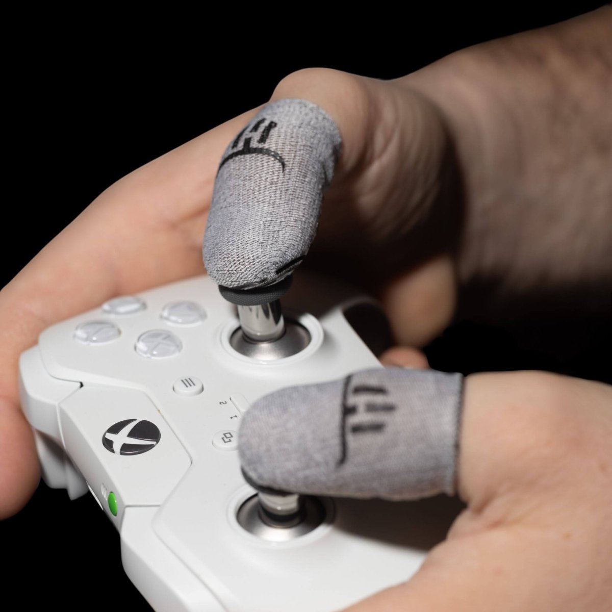 MinoanSocks Hand holding a gaming controller with thumbsticks, wearing gray finger sleeves.